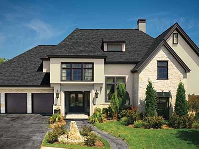 Front side of a beige mid-class home with black GAF shingles on its roof